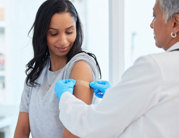 doctor placing a bandage on a a young woman in a clinic